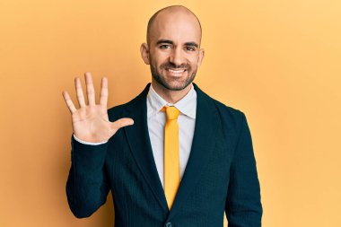 Genç İspanyol takım elbiseli ve kravatlı adam beş numarayı gösterip işaret ederken kendinden emin ve mutlu gülümsüyor.. 