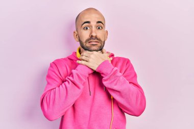 Spor kıyafetleri giyen ve kulaklık takan genç kel bir adam bağırıyor ve boğuluyor çünkü acı verici bir boğulma var. Sağlık problemi. Boğulma ve intihar konsepti. 