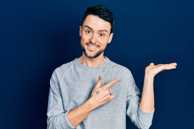 Gündelik kıyafetler giyen genç İspanyol adam kameraya hayret ediyor ve gülümsüyor.. 