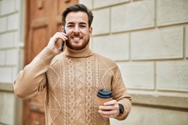 Kafkasyalı genç adam akıllı telefondan konuşuyor. Şehirde kahve içiyor..