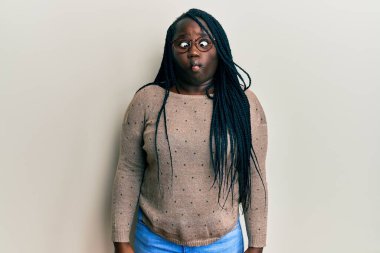 Örgülü, günlük kıyafetler ve gözlüklü genç siyah kadın dudaklarıyla balık yüzü yapıyor, çılgınca ve komik bir jest. Komik ifade. 