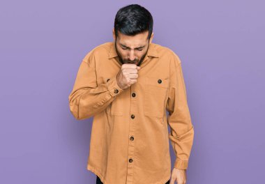 Günlük kıyafetler giyen genç İspanyol adam kendini iyi hissetmiyor ve soğuk algınlığı veya bronşitin belirtisi olarak öksürüyor. sağlık hizmeti kavramı. 