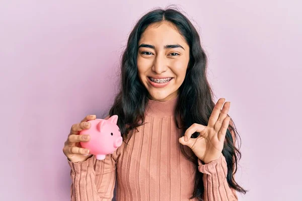 Menina Adolescente Hispânica Com Aparelho Dentário Segurando Banco Porquinho Fazendo — Fotografia de Stock