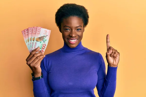Joven Chica Afroamericana Sosteniendo 100 Billetes Nuevos Zealand Dólares Sonriendo —  Fotos de Stock