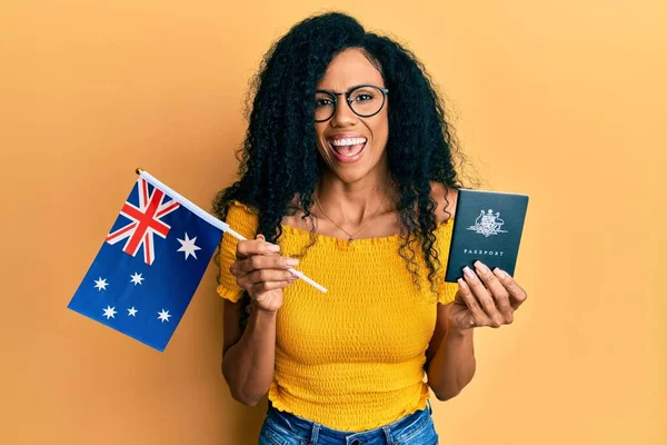 オーストラリアの国旗とパスポートを持つアフリカ系アメリカ人の中年女性はクレイジーを祝い 興奮して叫んで目を開けて成功に驚いています — ストック写真