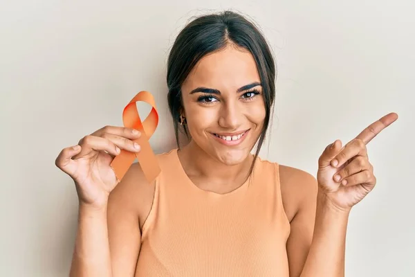 Joven Morena Sosteniendo Conciencia Naranja Cinta Sonriente Feliz Señalando Con — Foto de Stock