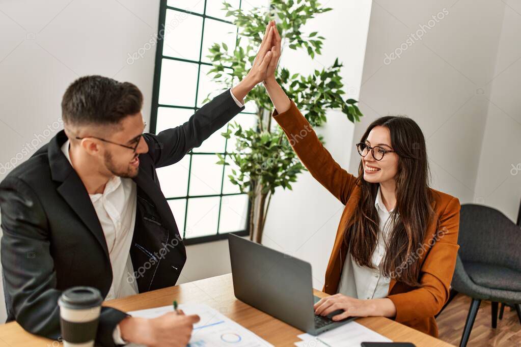 Two business executives raised up hands hitting five at the office.