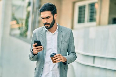 Zeki telefon kullanan ve şehirde kahve içen Latin asıllı genç bir işadamı..