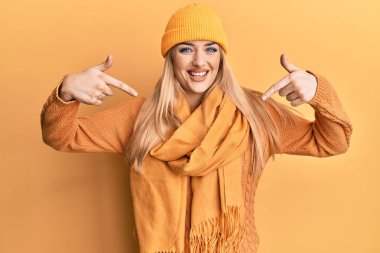 Kafkasyalı genç bir kadın yün kazak ve kep giyiyor. Kendine güveniyor gibi görünüyor. Yüzünde gülümseme, kendini gururlu ve mutlu bir şekilde gösteriyor.. 