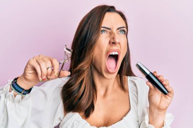 Kirpik bigudisi tutan genç esmer kadın kızgın ve kızgın çığlık atıyor hayal kırıklığına uğramış ve öfkeli, öfkeyle bağırıyor.. 