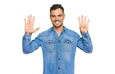 Günlük kot ceket giyen genç İspanyol adam dokuz numaralı parmaklarını gösterip gösterirken kendinden emin ve mutlu gülümsüyor.. 