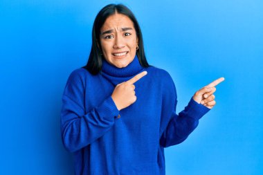 Asyalı genç bir kadın, sıradan bir süveter giyiyor. Endişeli ve gergin, endişeli ve şaşırmış bir ifade takınıyor. 