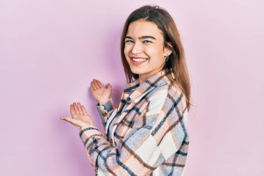 Günlük kıyafetler giyen genç beyaz kız gülümseyerek doğal bir şekilde içeri girmeye davet ediyor. 