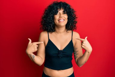 Kolsuz tişörtlü, sıradan giyinen, kendine güvenen, gülümseyen, kendini gururlu ve mutlu gösteren genç İspanyol kadın.. 