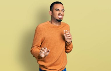 Genç Afro-Amerikan adam günlük giysiler giyiyor, tiksindirici ifadeler takınıyor, tiksindirici ifadeler takınıyor, tiksindirici ifadeler takınıyor.. 
