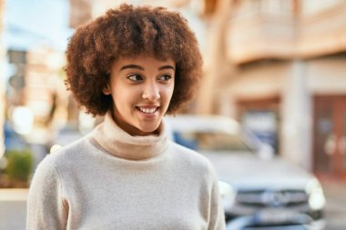 Genç İspanyol kız gülümseyerek şehirde mutlu mesut dikiliyor..