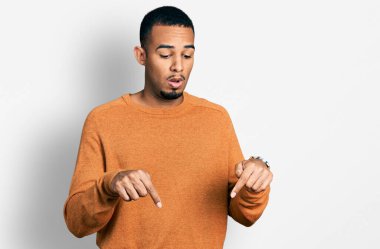 Gündelik giysiler giymiş genç Afro-Amerikan bir adam parmaklarını göstererek reklamını yapıyor, şaşırmış yüzünü ve ağzını açıyor. 