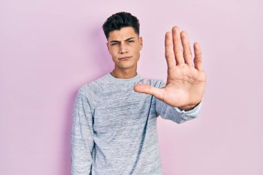 Günlük kıyafetler giyen genç İspanyol adam avucunun içi gibi şarkı söylemeyi kesiyor. Yüzünde olumsuz ve ciddi bir jest olan uyarı ifadesi. 