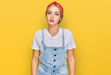 Günlük kıyafetler giyen genç beyaz kız yüzünde ciddi bir ifadeyle rahatladı. Basit ve doğal bir şekilde kameraya bakıyorsun.. 