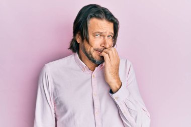 Orta yaşlı, iş gömleği giyen, gergin ve elleri ağızda tırnak yiyen yakışıklı bir adam. anksiyete. 