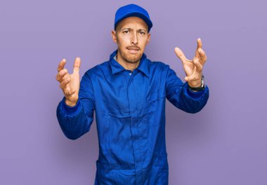 Kel, sakallı, işçi tulumu giyen, öfkeden kudurmuş, elleri boğazlamaya çalışan, deli gibi bağıran bir adam. 