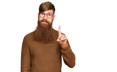 Genç İrlandalı kızıl elbiseli ve gözlüklü bir adam bir numaralı parmağını gösterip işaret ederken kendinden emin ve mutlu bir şekilde gülümsüyor.. 