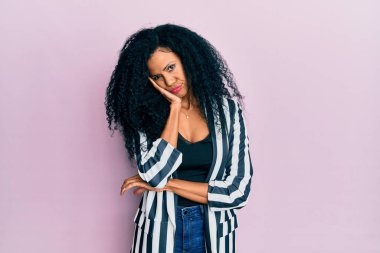 Orta yaşlı Afro-Amerikalı kadın gündelik kıyafetler giyip kollarını kavuşturarak depresyondan sıkılmış ve yorgun görünüyor.. 
