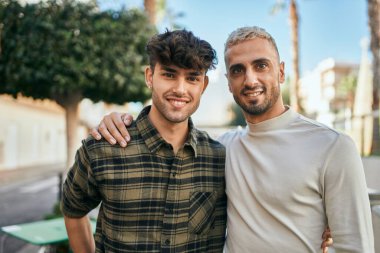 Mutlu bir şekilde gülümseyen ve şehirde sarılan genç eşcinsel çift..