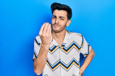 Gündelik kıyafetler giyen genç İspanyol adam İtalyan jesti yapıyor. El ve parmaklarıyla kendinden emin ifade ediyor. 