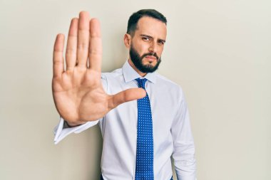 İş kravatı takan sakallı genç adam avucuyla şarkı söylemeyi kesiyor. Yüzünde olumsuz ve ciddi bir jest olan uyarı ifadesi. 