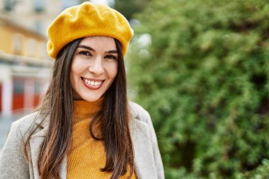 Genç İspanyol kız gülümseyerek şehirde mutlu mesut dikiliyor..