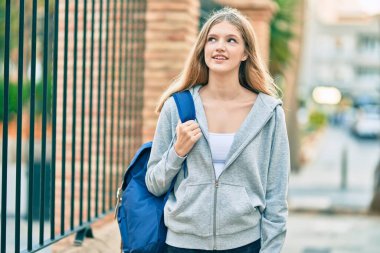 Güzel, beyaz bir genç, gülümsüyor, mutlu bir şekilde şehirde duruyor..