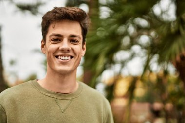 Genç İspanyol adam gülümseyerek şehirde mutlu mesut dikiliyor..