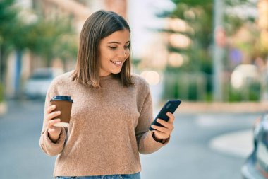 Genç İspanyol kadın akıllı telefon kullanıyor. Şehirde kahve içiyor..