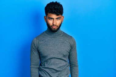 Balıkçı yaka kazak giyen sakallı bir Arap sıkıntılı ve endişeli, sinirli ve korkmuş bir şekilde ağlıyor. hüzünlü ifade. 