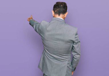 Orta yaşlı bir adam iş kıyafetleri içinde geriye doğru poz veriyor. 