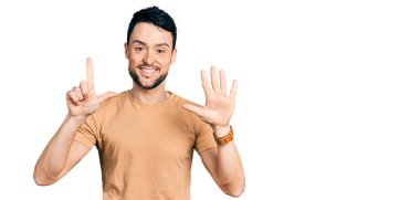 Sakallı, sıradan tişörtlü İspanyol bir adam yedi numarayı gösterip işaret ederken kendine güvenen ve mutlu bir şekilde gülümsüyor.. 