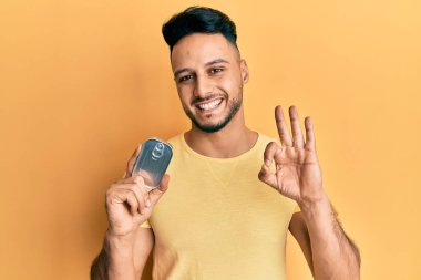 Elinde konserve yiyecek tutan genç Arap adam parmaklarıyla imza atıyor, gülümseyerek mükemmel bir sembol oluşturuyor. 