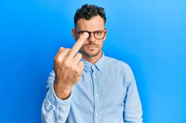 Young hispanic man wearing casual clothes and glasses showing middle finger, impolite and rude fuck off expression 