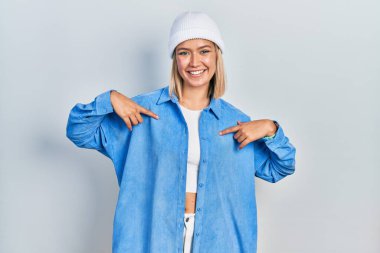 Güzel sarışın kadın yün şapka takıyor kendine güvenen, yüzünde gülümseme olan, kendini gururlu ve mutlu gösteren.. 