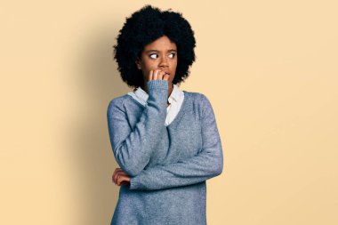 Genç Afro-Amerikalı kadın iş kıyafetleri giyiyor. Stresli ve gergin görünüyor. Elleri ağızdan tırnak yiyor. anksiyete. 