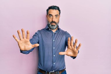 Sakallı, gri saçlı, iş kıyafetleri giyen, korkudan dehşete düşmüş orta yaşlı bir adam. El hareketlerini bırak, şok içinde bağır. panik konsepti. 