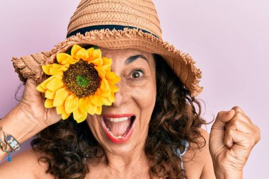 Orta yaşlı İspanyol kadın, yaz şapkası takmış, ayçiçeğini gözüne bastırmış gururla bağırıyor, zaferi ve başarıyı kutluyor. 
