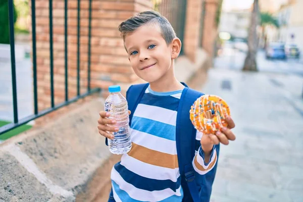 Uroczy Biały Student Chłopiec Uśmiechnięty Szczęśliwy Trzymając Pączka Butelkę Wody — Zdjęcie stockowe
