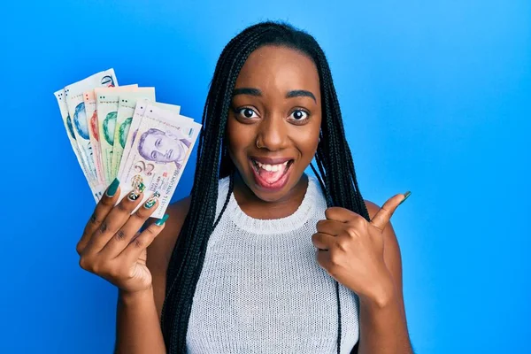 Joven Mujer Afroamericana Sosteniendo Billetes Dólar Singapur Apuntando Con Pulgar —  Fotos de Stock