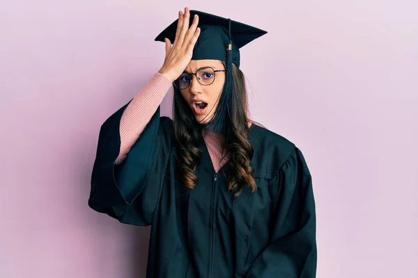 若いヒスパニック系の女性が卒業キャップと式のローブを頭の上に手でミスのために驚いて エラーを覚えて着用 忘れられた悪い記憶の概念 — ストック写真