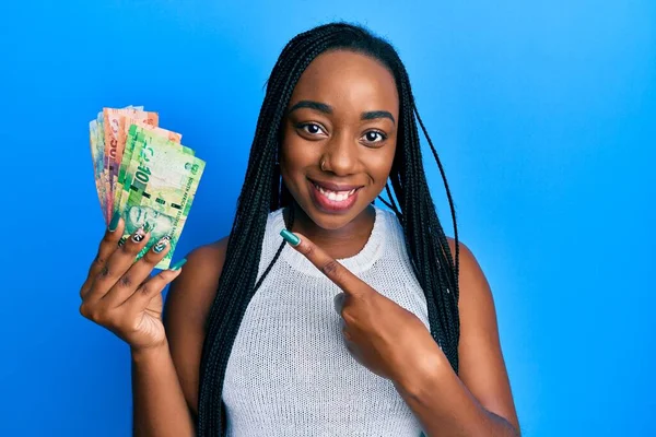 Joven Mujer Afroamericana Sosteniendo Billetes Rand Sudafricanos Sonriendo Feliz Señalando —  Fotos de Stock
