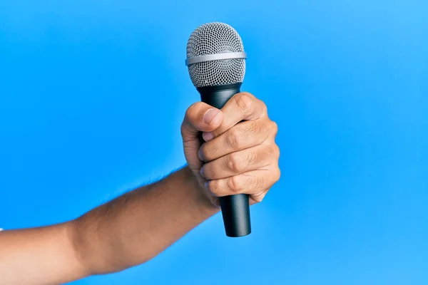 Hand Latinamerikansk Man Håller Mikrofon Över Isolerad Blå Bakgrund — Stockfoto