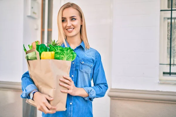 Joven Chica Rubia Sonriendo Feliz Sosteniendo Comestibles Bolsa Papel Pie —  Fotos de Stock