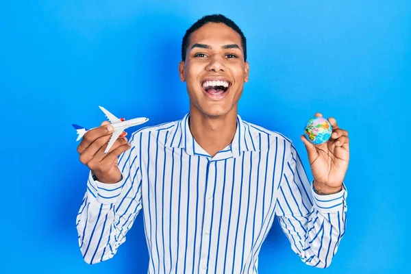 Νεαρός Αφροαμερικάνος Που Κρατάει Χάρτινο Αεροπλάνο Και Παγκόσμια Μπάλα Χαμογελώντας — Φωτογραφία Αρχείου